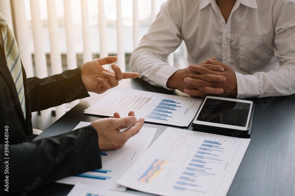 A group of professional business people sit on a meeting table in the