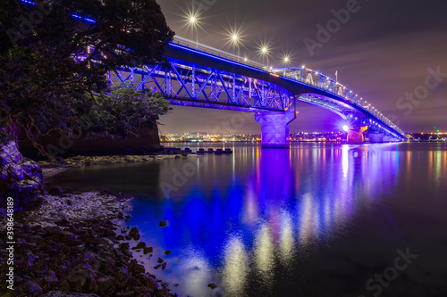 The Auckland Harbour Bridge, Auckland, New Zealand, with colorful nighttime lighting, reflected in the waters of Waitemata Harbour photo
