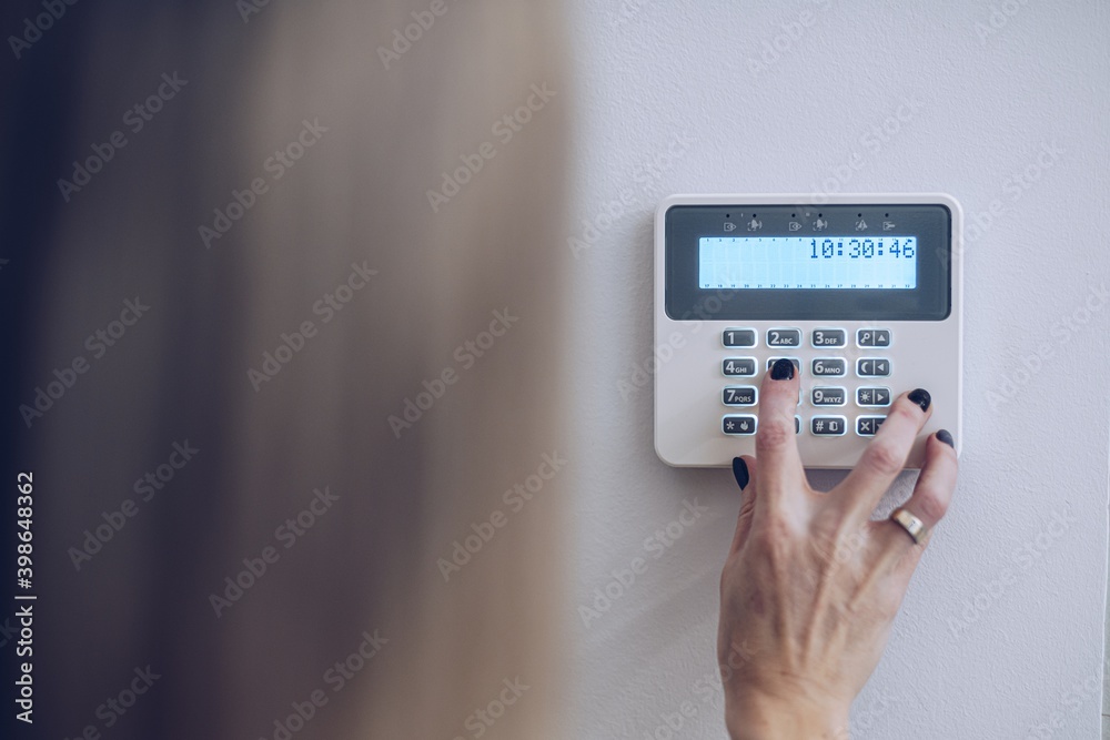 Security home system. Woman entering secret code on home alarm Security home system. Woman entering secret code on home alarm