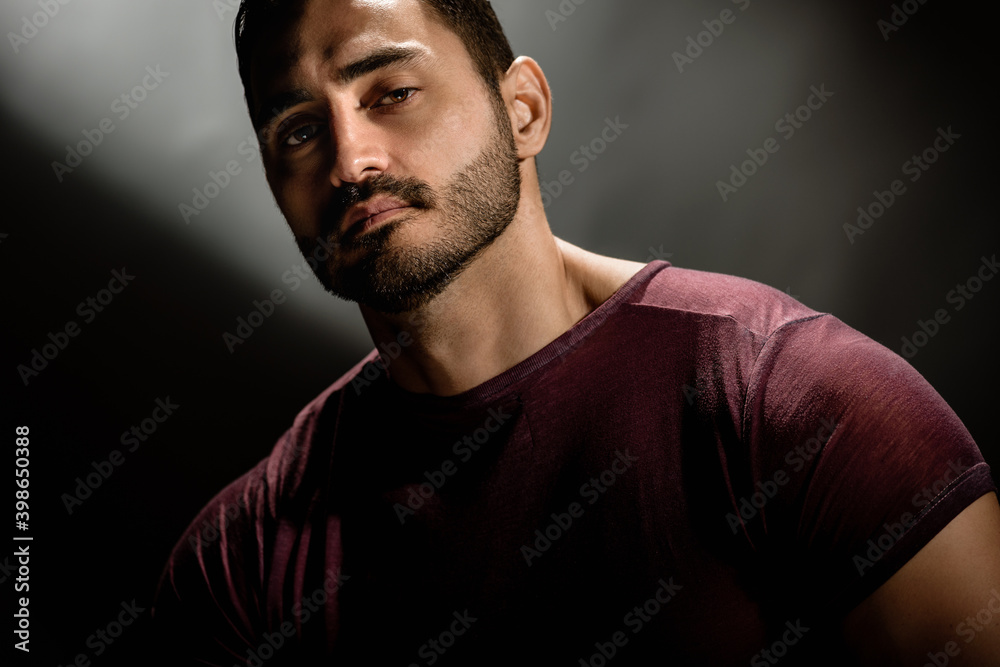 Portrait of brutal handsome male model posing on black background