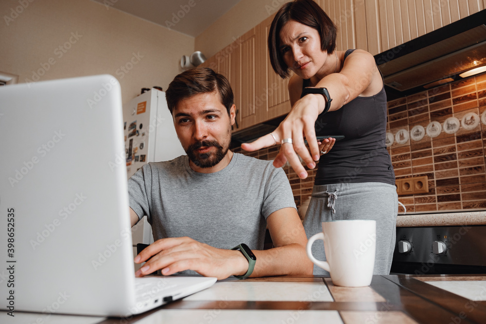 Couple at kitchen, reading news and using laptop. Couple at kitchen, reading news and using laptop.
