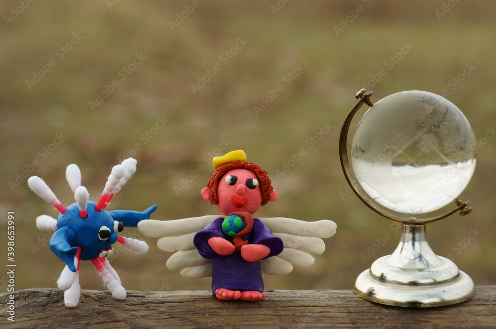 Fototapeta premium An angel figurine and a small glass globe. Next to the figure of the virus.