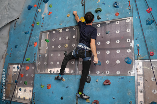 Active sporty man practicing rock climbing on artificial rock in a climbing wall. Extreme sports concept.