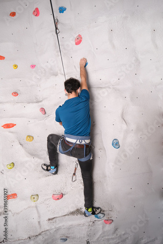 Active sporty man practicing rock climbing on artificial rock in a climbing wall. Extreme sports concept.
