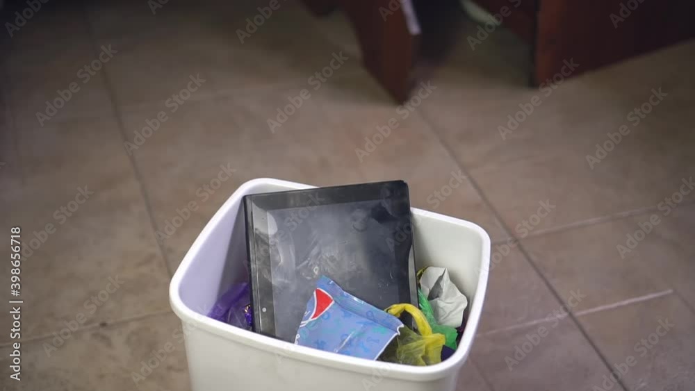 A woman throws tablet with broken screen in a regular trash bin