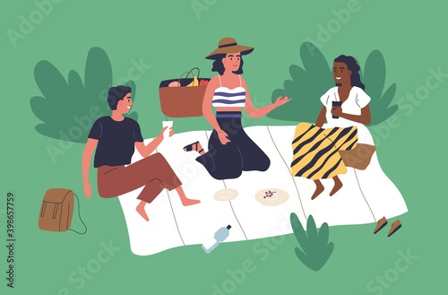 Happy young friends sitting on blanket in park and chatting. Scene of summer ...