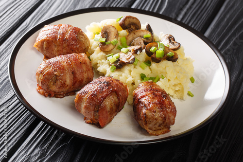 Slavink is ground meat, wrapped in bacon and fried in butter and lard served with mashed potatoes and mushrooms closeup in the plate on the table. horizontal photo