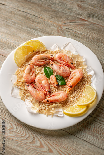 A plate with a frozen ready made dish of rice and shrimp with lemon on a wooden table. Concept of a delicious food, like in a restaurant, that can be prepared fast