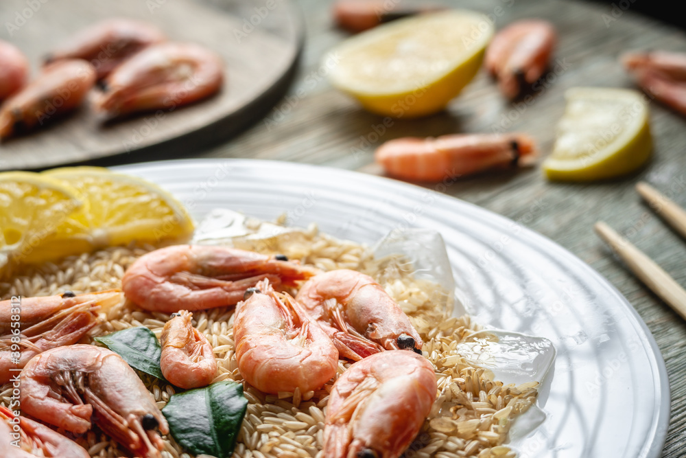 Appetizing delicious frozen dish of shrimps and rice with lemon on a wooden table. Concept of ready made frozen food for dinner like in a restaurant at home. Closeup