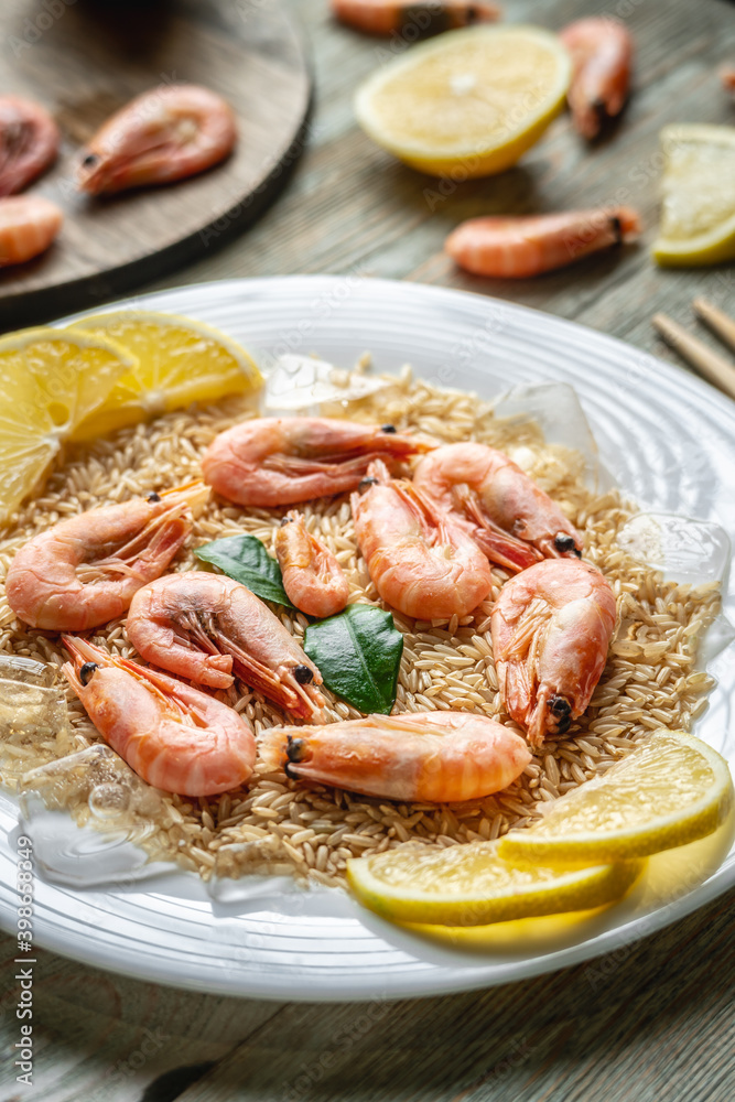 Appetizing delicious frozen dish of shrimps and rice with lemon on a wooden table. Concept of ready made frozen food for dinner like in a restaurant at home Appetizing delicious frozen dish of shrimps and rice with lemon on a wooden table. Concept of ready made frozen food for dinner like in a restaurant at home