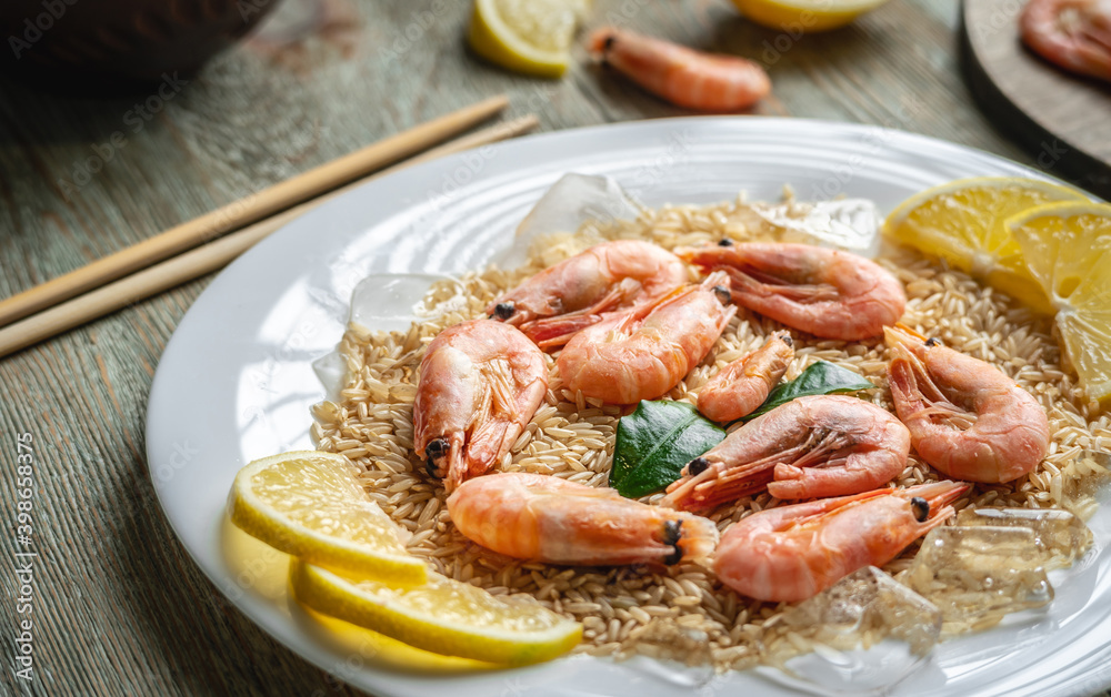 Appetizing delicious frozen dish of shrimps and rice with lemon on a wooden table. Concept of ready made frozen food for dinner like in a restaurant at home Appetizing delicious frozen dish of shrimps and rice with lemon on a wooden table. Concept of ready made frozen food for dinner like in a restaurant at home