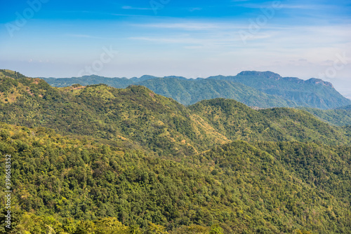 Mountain view morning on top hills and green forest cover with soft mist and blue sky background.Thailand.