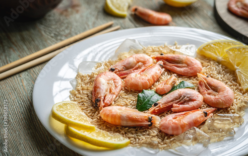 Appetizing delicious frozen dish of shrimps and rice with lemon on a wooden table. Concept of ready made frozen food for dinner like in a restaurant at home