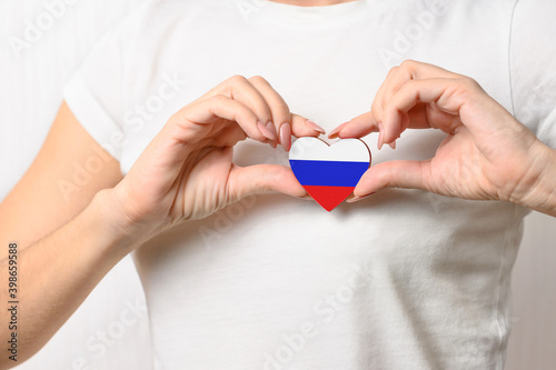 Love Russia. The girl holds on her chest in her hands a heart in the form of a flag of Russia. Patriotism concept