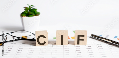 CIF word concept written on wooden blocks, cubes on a light table with flower ,pen and glasses on the chart background photo