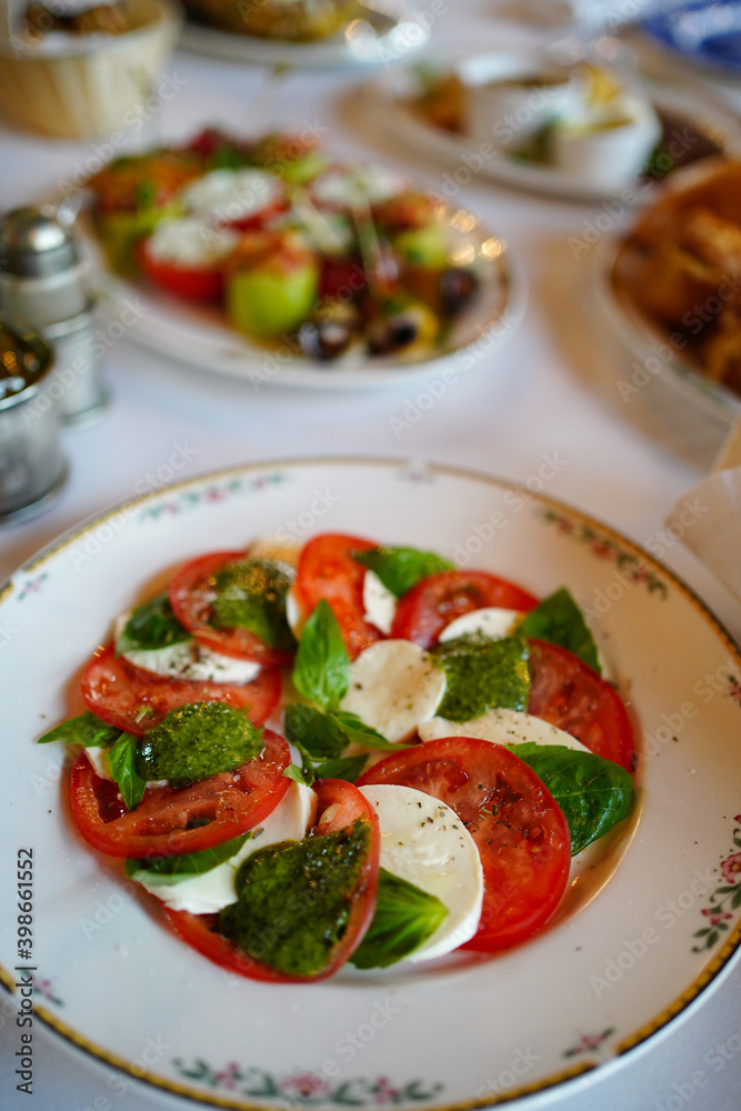 slicing tomatoes and mozzarella cheese with basil and spices on a plate. slicing tomatoes and mozzarella cheese with basil and spices on a plate.