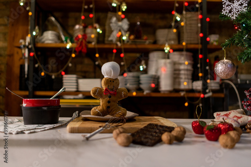 Vegan chef girl cooking sweets in Christmas kitchen next to stuffed cookie doll playing and enjoying