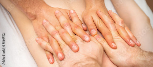 4 hands massage the patient back. Two masseurs doing massage. Closeup © okskukuruza