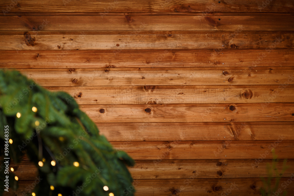 Brown wooden background with unfocused fir branches and warm golden garland lights bokeh. Framed holiday template, copy space. Merry Christmas, New Year. Brown wooden background with unfocused fir branches and warm golden garland lights bokeh. Framed holiday template, copy space. Merry Christmas, New Year.