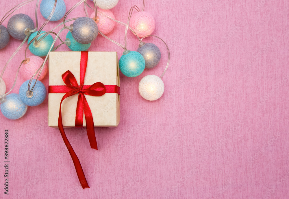 gift box with red ribbon on pink background. Garland. Copy space