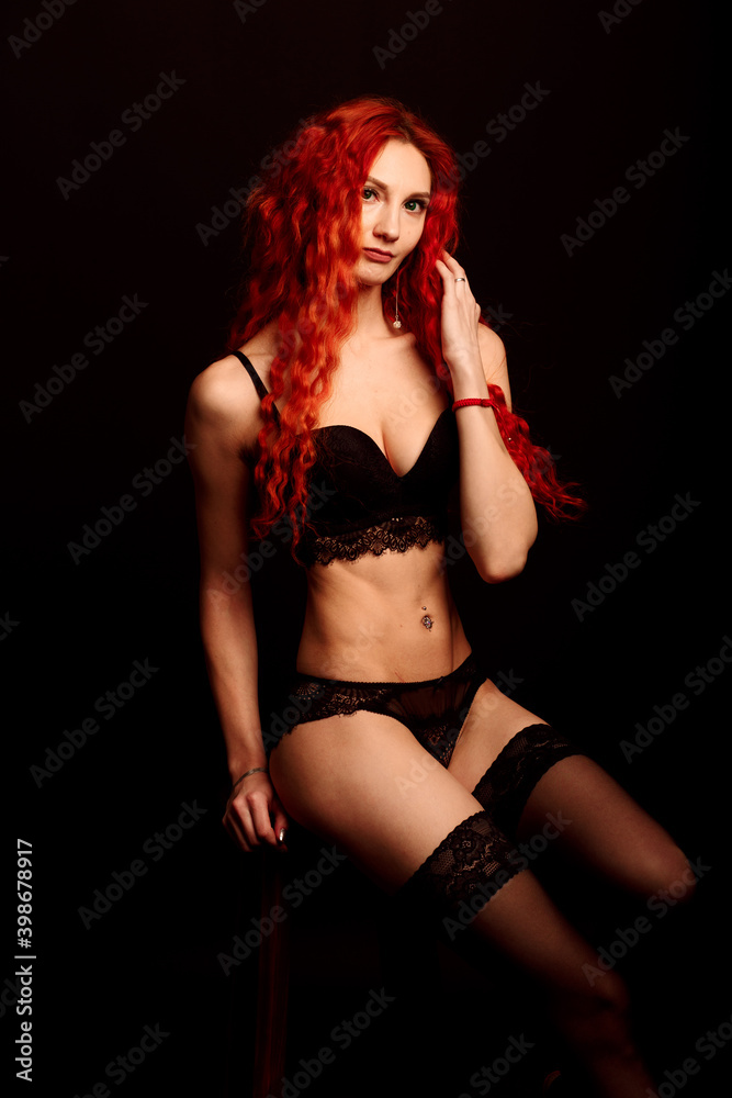 Young intimate redhead woman beauty portrait against black background.