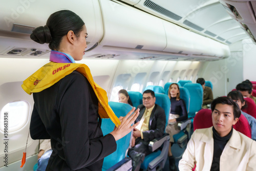 Fotografia, Obraz Asian Air hostess staff airline demonstrate safety procedures to passengers prior to flight take off in cabin airplane
