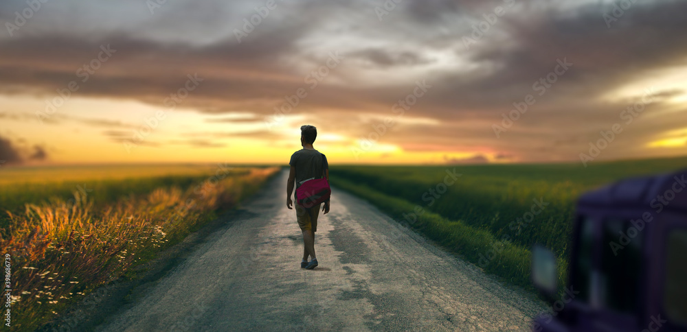 a young man on a road trip in the open valley at sunset landscape.