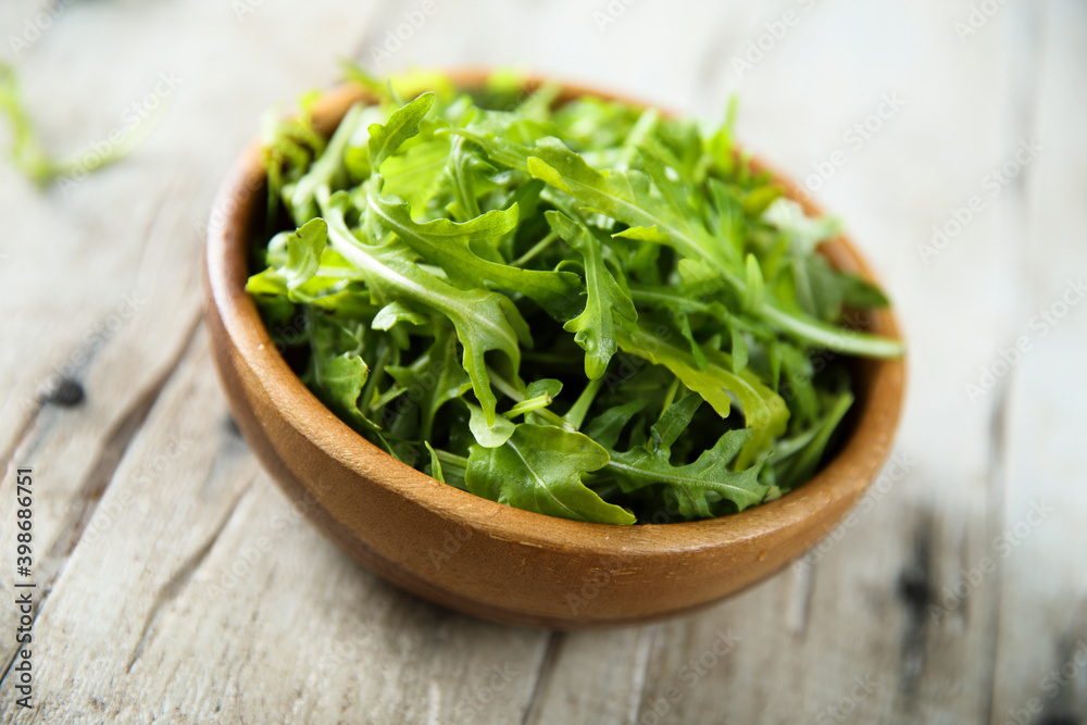 Healthy fresh arugula in a wooden bowl Healthy fresh arugula in a wooden bowl