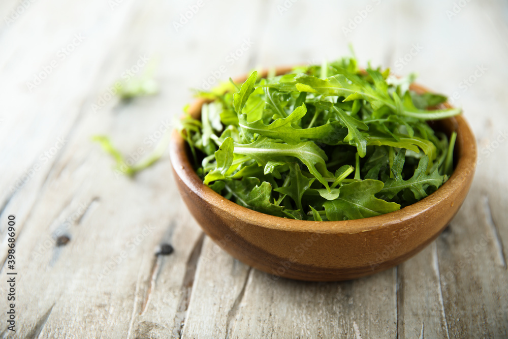 Healthy fresh arugula in a wooden bowl Healthy fresh arugula in a wooden bowl