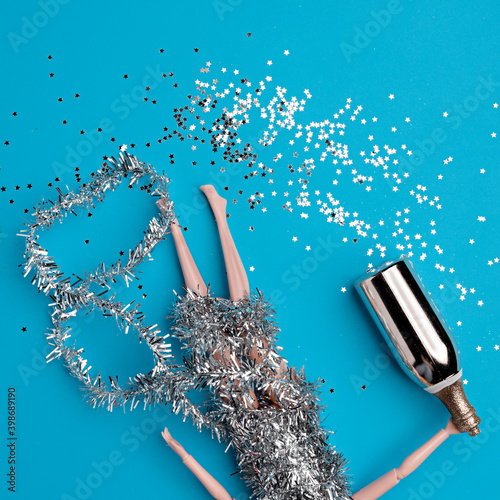 Young woman lying on blue background deadly drunken holding bottle of champagne. Female intoxicated with alcohol after tough night party. Alcoholism habitual drunkenness pernicious habit concept.