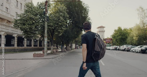 Wallpaper Mural a young hipster man crosses the city street with a backpack. Sloe motion 4k. Torontodigital.ca