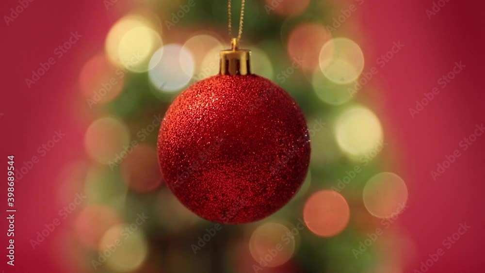 Close up of a Christmas ball decoration in first ground and a Christmas tree on the background Close up of a Christmas ball decoration in first ground and a Christmas tree on the background