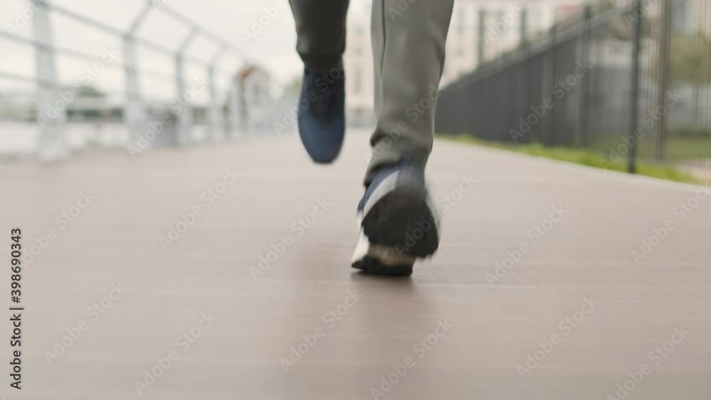 Close up of legs of unrecognizable jogger wearing sport clothes and sneakers running along embankment Close up of legs of unrecognizable jogger wearing sport clothes and sneakers running along embankment