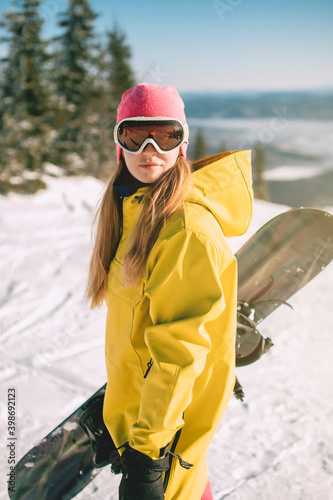 Woman with mask for snowboarding with mountains covered by snow in background. Girl skier wearing ski glasses in winter. Woman during winter vacation.
