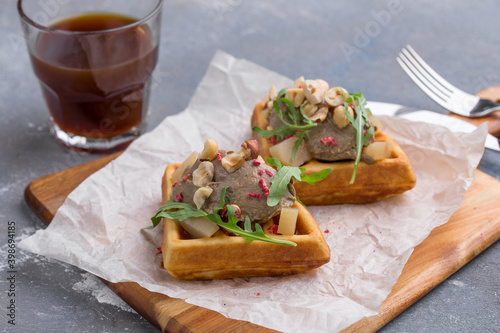 Belgian waffle with liver pate and hazelnut and glass of coffee on gray background