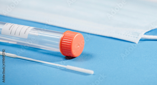 transparent vial transport tube with orange closure and adhesive for patient data, swab, mask, with blue background
