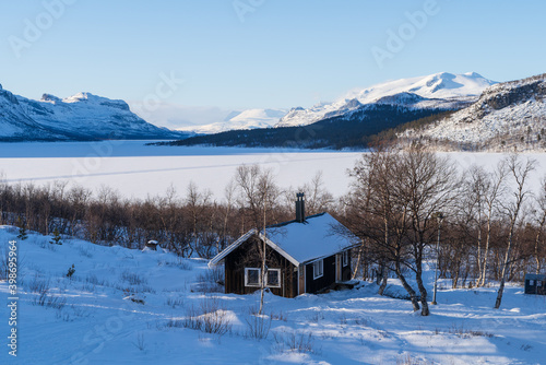 Cabin in the snow at a frozen lake in Lapland, Sweden.