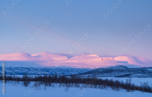 Mountains in the last, pink, sunlight of a winters day. Lapland, Sweden