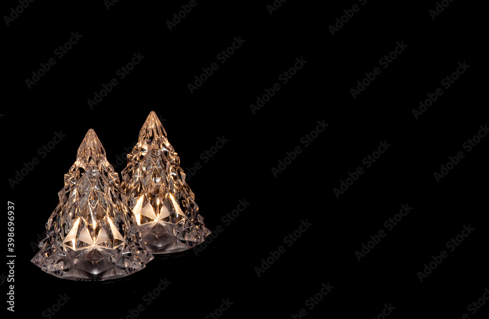 Two crystal christmas tree decoration elements isolated on dark background. With warm white light
Two crystal christmas tree decoration elements isolated on dark background. With warm white light