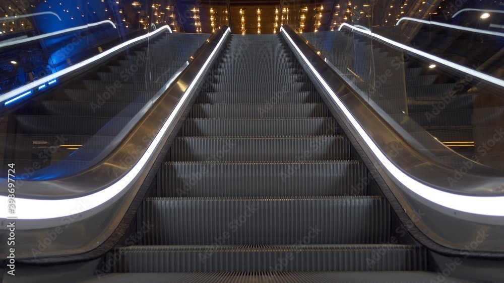 Close up of upward moving stairs with white lights on sides in business and shopping centre with no people around Close up of upward moving stairs with white lights on sides in business and shopping centre with no people around