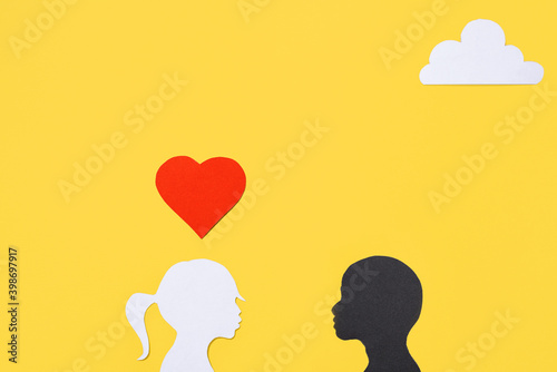 Concept for Valentine s Day  interracial love. Silhouettes of a girl and a boy  yellow background. Creative art love card. Flat lay  top view  copy space
