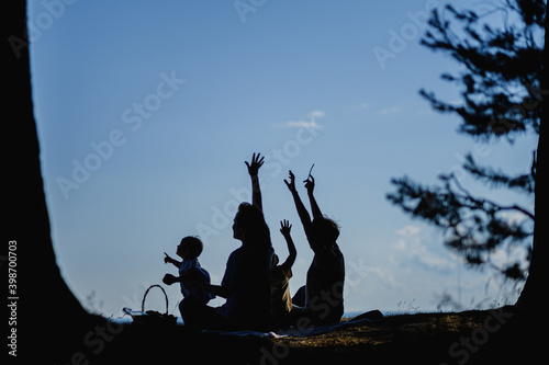 Homosexual lesbian family with two children, a son and a daughter. Two moms and kids at an outdoor picnic. Forest and sea.