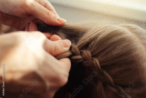 Mom is combing her daughter's hair. Taking care of baby's hair. The concept of a happy childhood and a good attitude towards children. Happy family