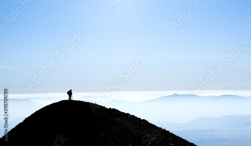 Silhouette of mountain with one hiker standing on top