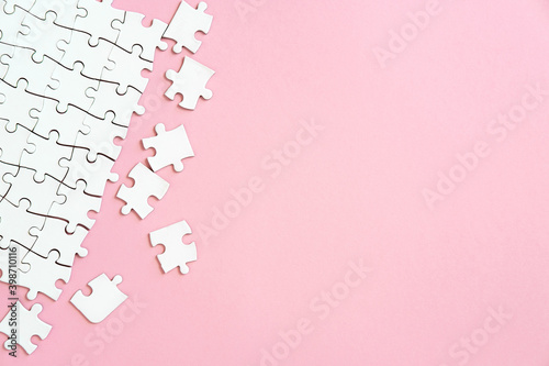 White jigsaw puzzle pieces in corner on pink background with copyspace photo