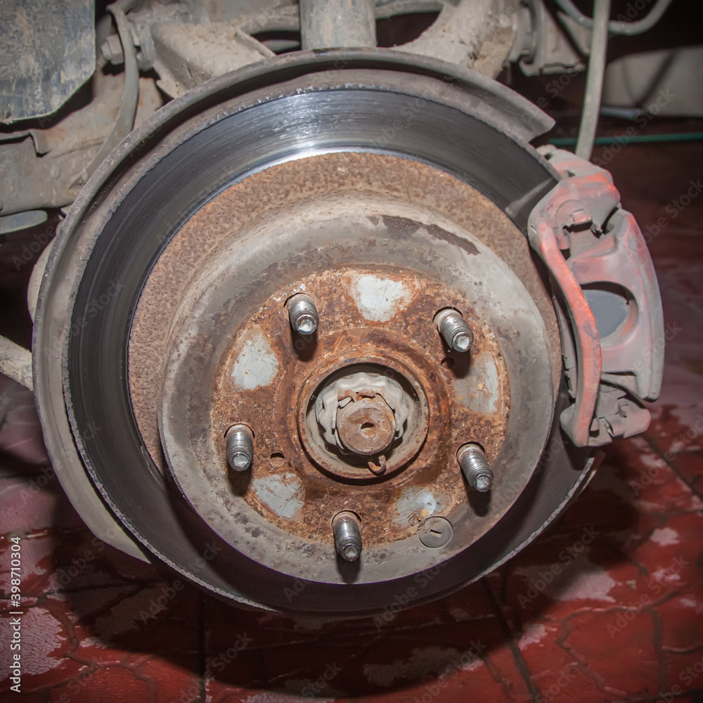 Rusty rear hub of a car wheel with a brake disc and caliper. A car without a wheel