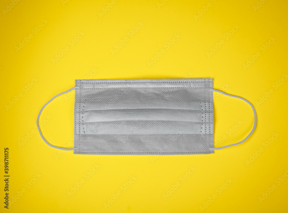 Gray medical mask on yellow background colors of the year 2021 concept Gray medical mask on yellow background colors of the year 2021 concept