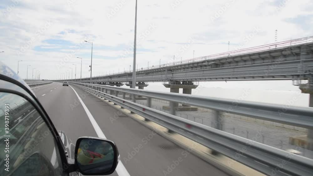 A car with tourists drives along the new Crimean Bridge, which passes through the Kerch Strait and connects Toman with the Crimean Peninsula A car with tourists drives along the new Crimean Bridge, which passes through the Kerch Strait and connects Toman with the Crimean Peninsula