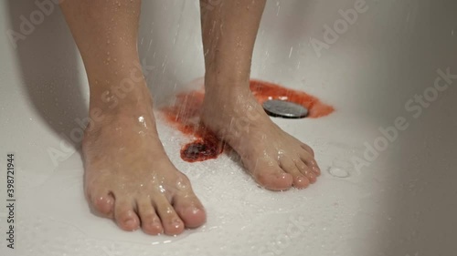 Women's feet in the shower. The water washes away the blood. Spontaneous miscarriage in the early stages.