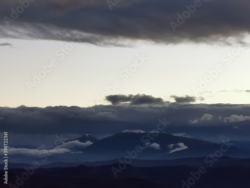 Cime innevate dei monti Appennini in un tramonto di nuvole scure e luce